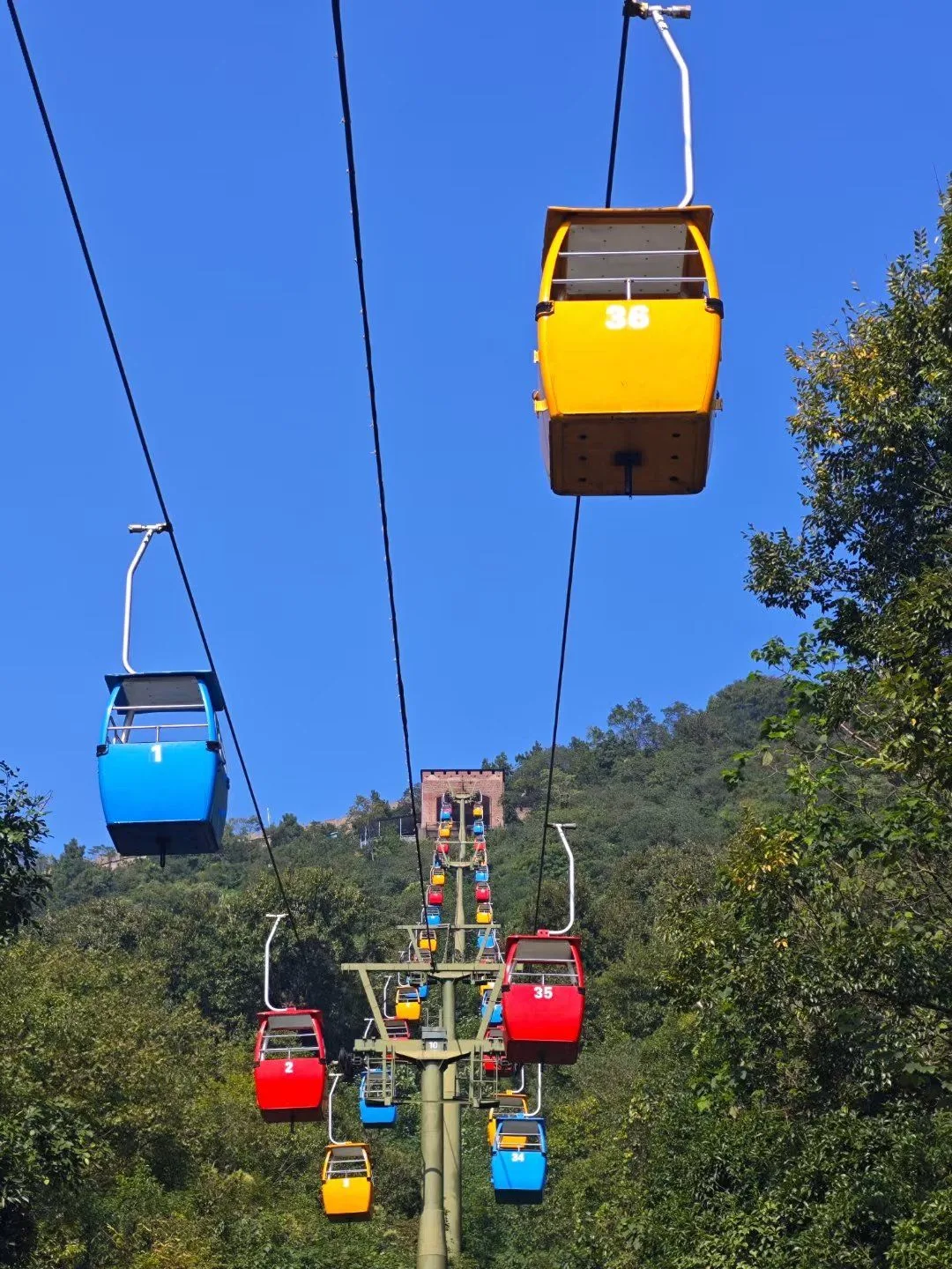 Colorful Badaling cable cars above green forest