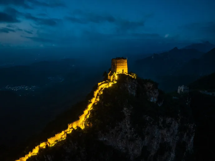 Great Wall tower lit at night on a steep ridge