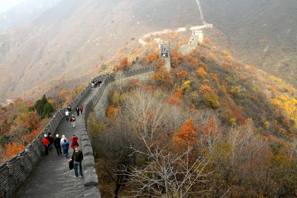 Visitors walking along a wide Great Wall section in autumn