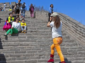 Traveler standing on the Great Wall while other visitors walk nearby