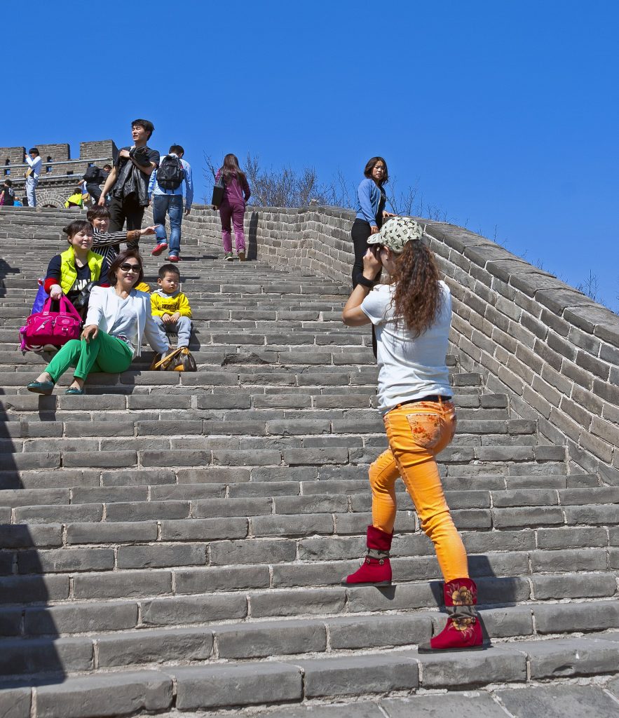 Traveler standing on the Great Wall while other visitors walk nearby