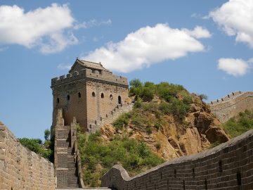 A stone watchtower and stairway at Jinshanling Great Wall under a blue sky