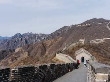 Visitors walking between watchtowers on the Mutianyu Great Wall above mountain ridges