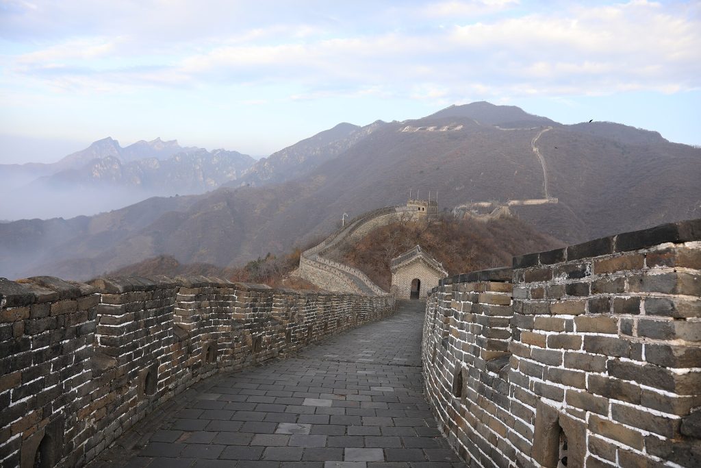 A broad stone walking route at Mutianyu leading toward a watchtower and forested mountains