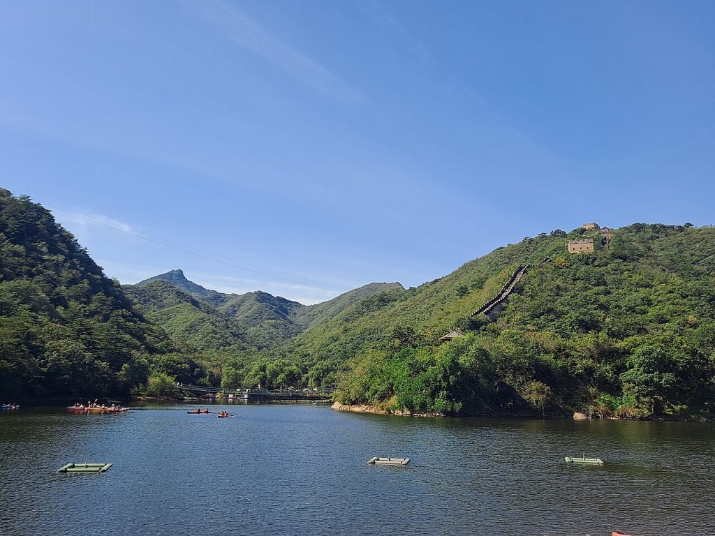 Lake water, floating platforms and the Great Wall on a green hillside at Huanghuacheng
