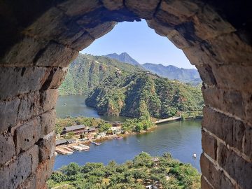Lake and moored boats seen through a stone watchtower window at Huanghuacheng Lakeside Great Wall