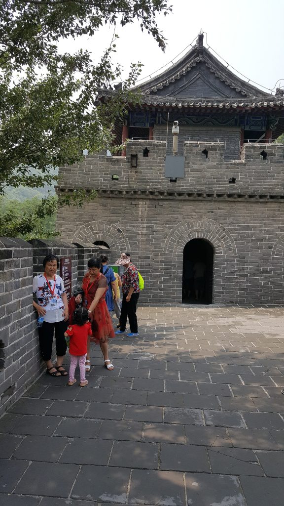 Stone arch and arrow tower at Shuiguan Great Wall with visitors in the courtyard